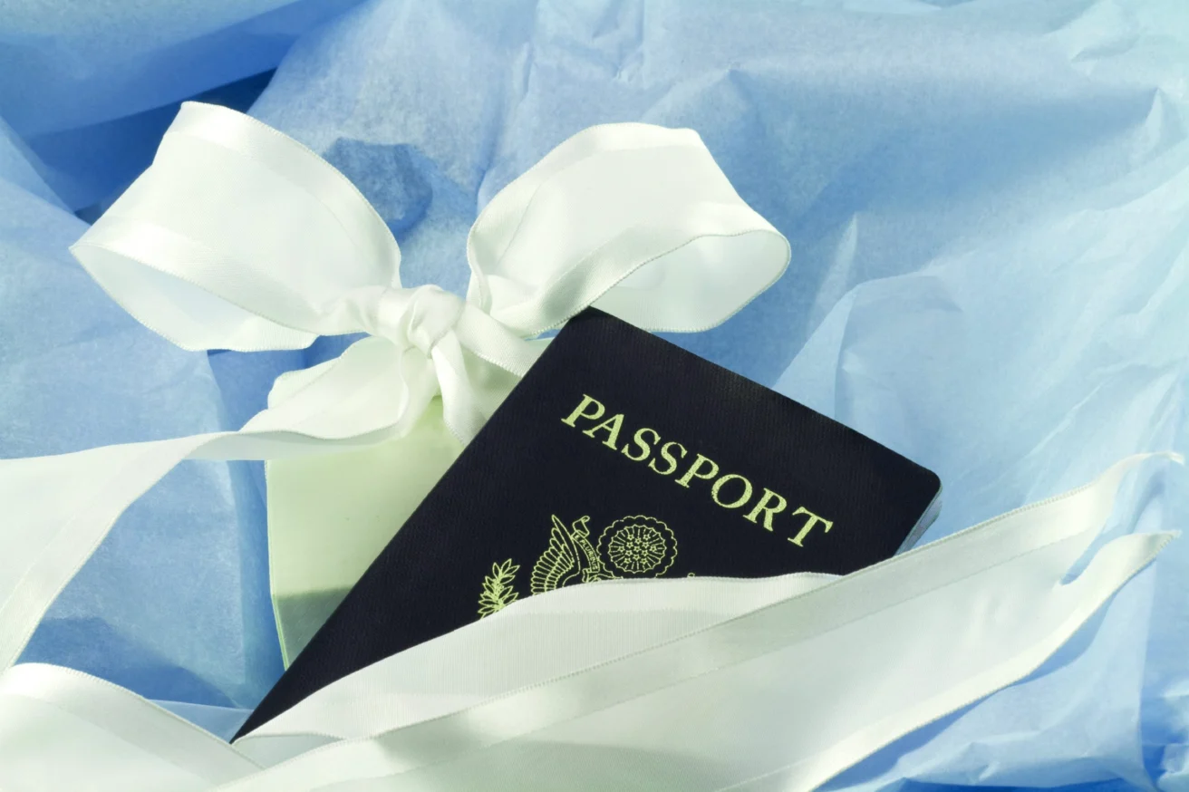 A passport wrapped with a white ribbon, set on blue fabric.