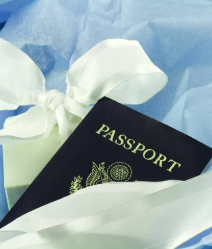 A passport wrapped with a white ribbon, set on blue fabric.