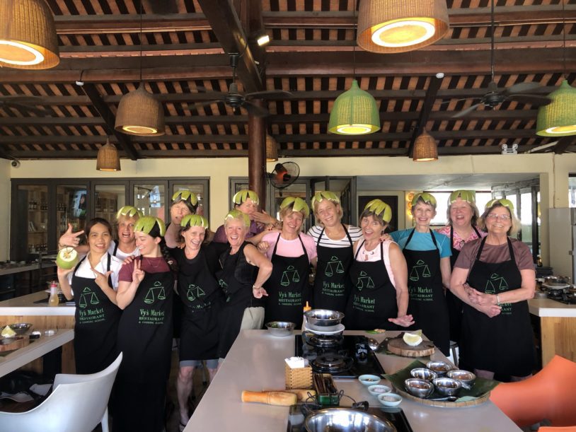Group photo of women wearing black aprons after a cooking class