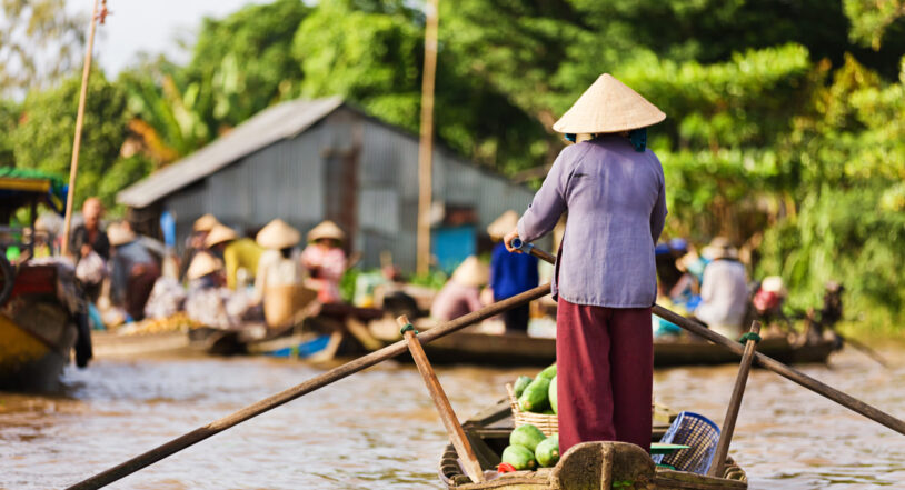 Vietnamese fruits seller - woman rowing boat in the Mekong river delta selling fruits, Vietnam.