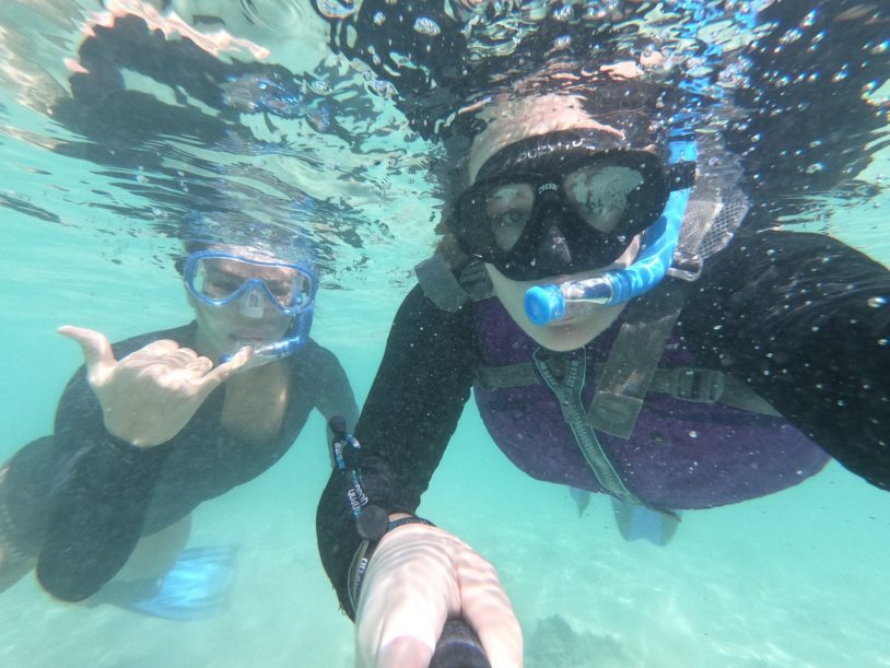 Two women with snorkeling masks looking into underwater camera