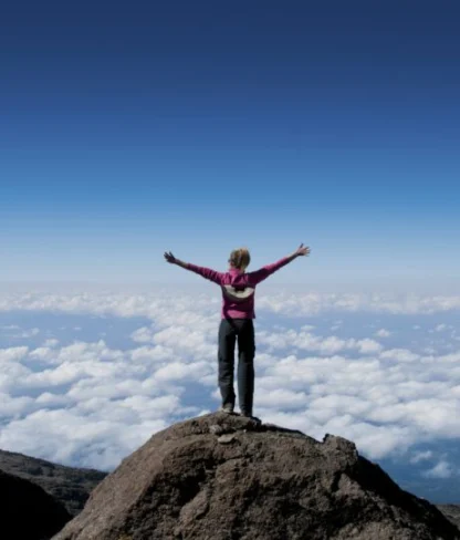 Woman atop a mountain.