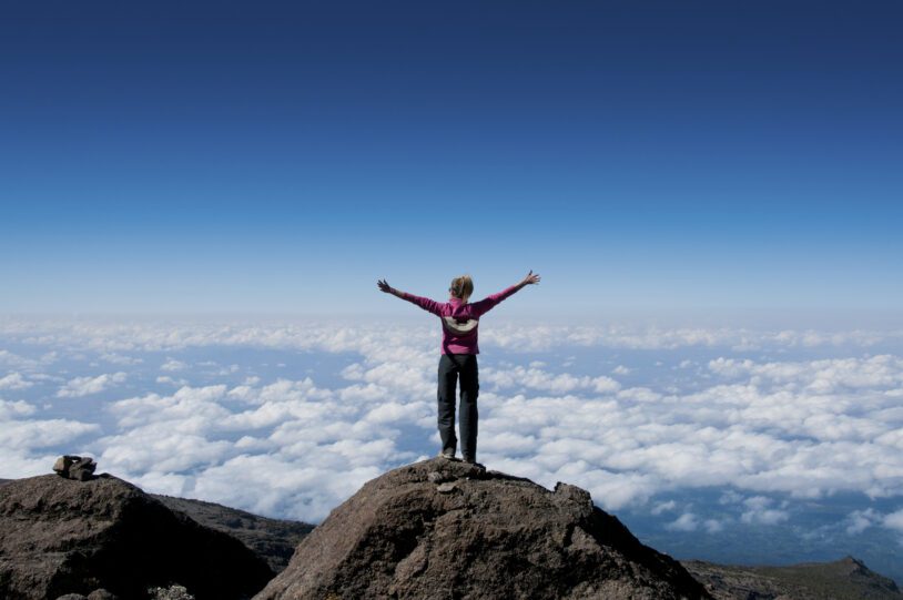 Woman atop a mountain.