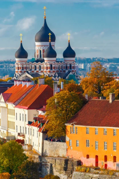 Colorful rooftops and medieval architecture of Tallinn, Estonia, with the Alexander Nevsky Cathedral and a tower visible against a clear sky.