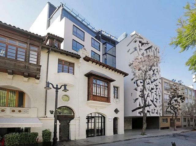 Street view of a mix of traditional and modern architecture, featuring older buildings with ornate facades alongside a contemporary structure with geometric designs.