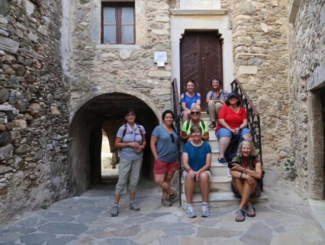 Group of seven people posing on stone steps in front of an old stone building.