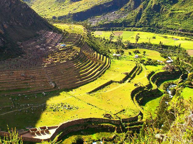 Terraced fields and ancient stone structures are nestled in a lush green valley with surrounding hills.