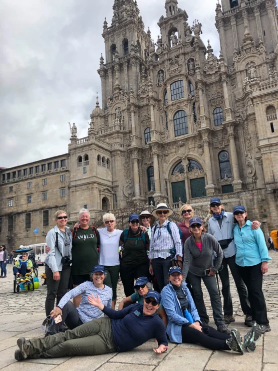 A group of people poses in front of a historic cathedral with ornate architecture under a cloudy sky.