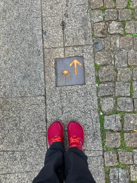 Red shoes standing on a stone path with yellow shell and arrow symbols pointing forward.