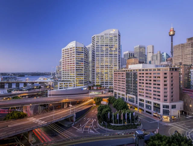 Cityscape view with tall buildings, intersecting highways, and a distinctive tower against a twilight sky.