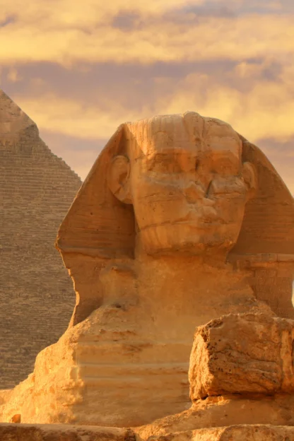 The image shows the Great Sphinx and a pyramid in Giza, Egypt, under a cloudy, golden sky.