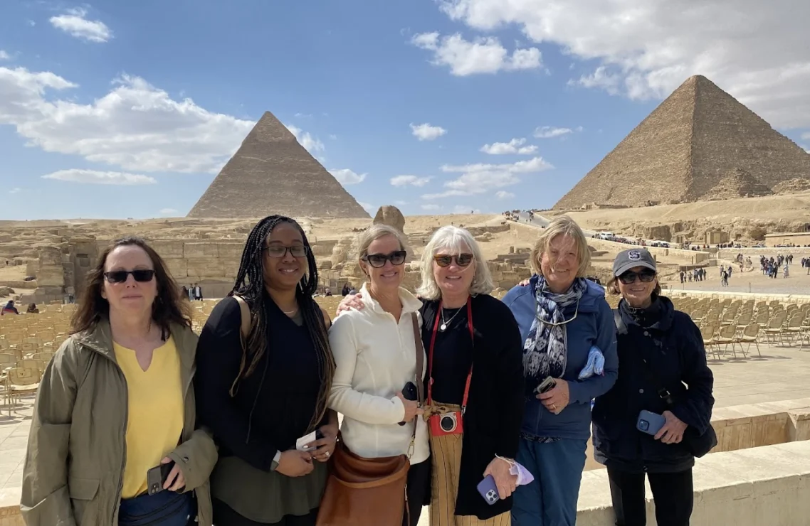 Six people standing in front of the Pyramids of Giza, smiling at the camera.