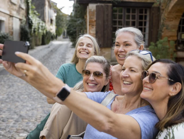 Five women smiling while taking a selfie on a cobblestone street.