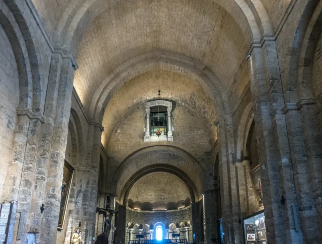 Interior of an ancient stone church with high arched ceilings and light illuminating from a small window above.