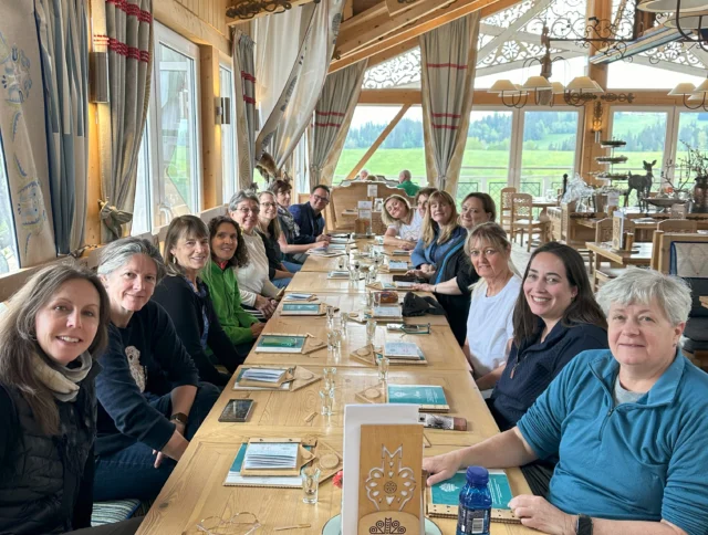 A group of people sitting together at a long table in a wooden restaurant setting.