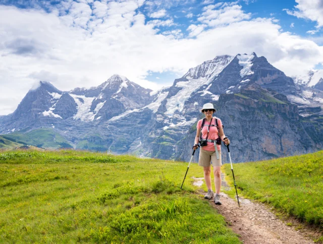 Switzerland Travel - Senior Asian woman hiking through the the Mountain view trail in the Swiss Alps in the Jungfrau region.