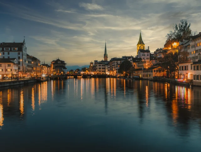 illuminated cityscape of old town zurich along the river at blue hour