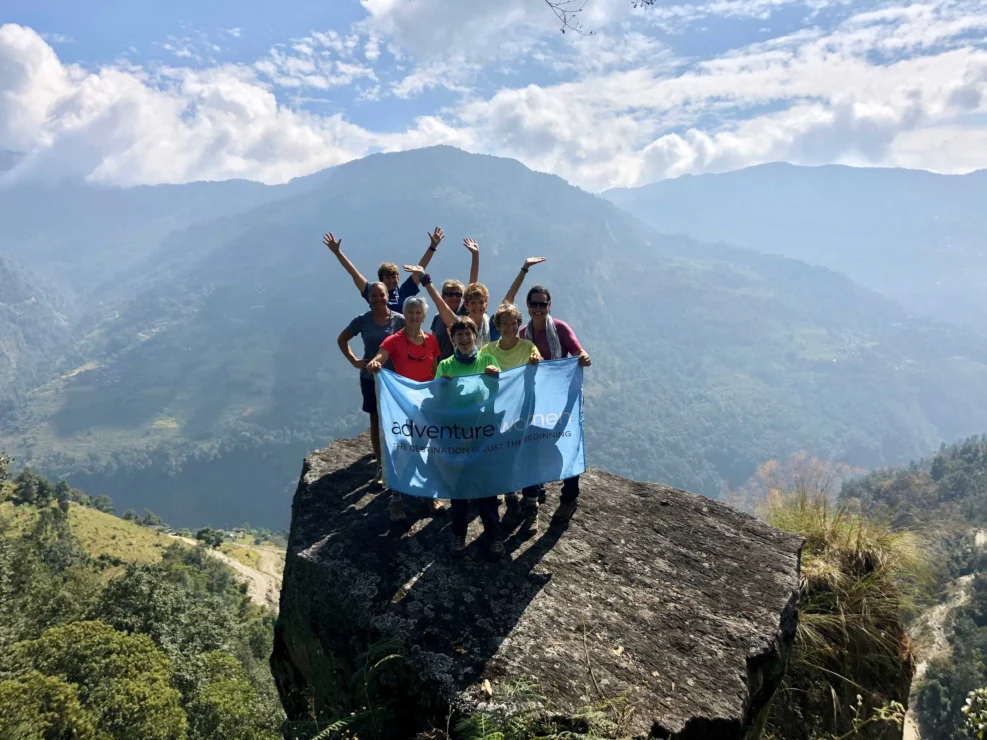 A group of women holding an Adventure Women flag on a mountain.