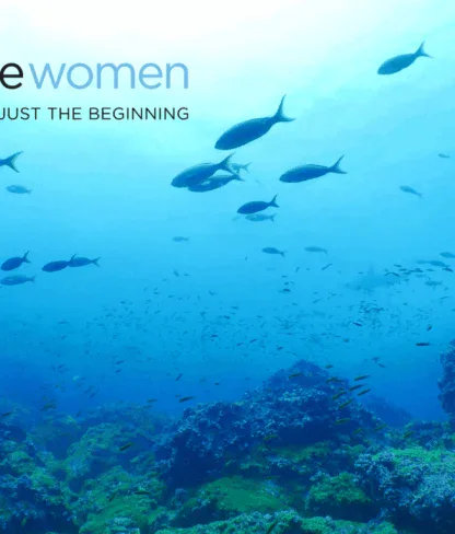 A school of fish swims above a rocky coral reef in clear blue ocean water; the text reads "adventure women—The destination is just the beginning.